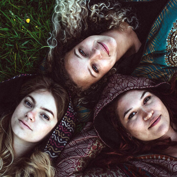 3 girls laying on grass wearing Emma's Emporium boho hippie style clothes